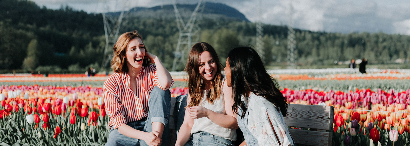 Three girls talking and laughing about great custom web design in a field of flowers